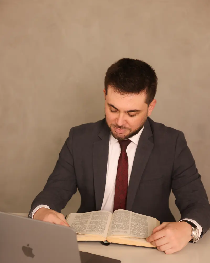Eduardo Baldissera Carvalho Salles lendo um livro à mesa de trabalho